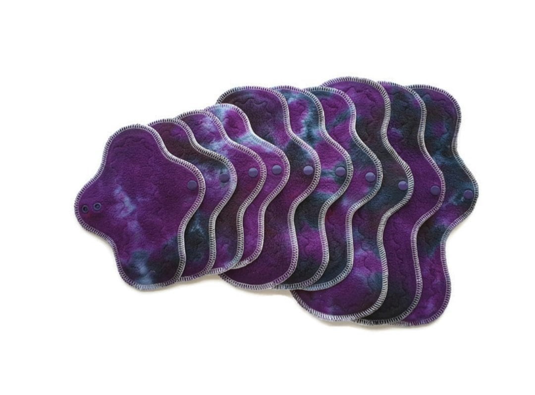 A bundle of organic wool backed cloth menstrual pads with hand-dyed purple galaxy organic cotton sherpa tops and kam snap closures.